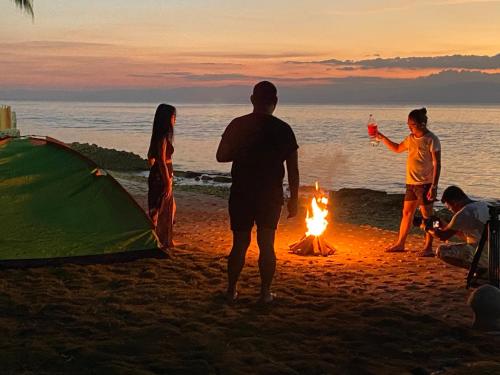 a group of people standing around a campfire on the beach at Rio Beach Resort in Alegria