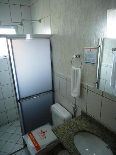 a bathroom with a sink and a toilet and a mirror at Bravo City Rondonópolis in Rondonópolis