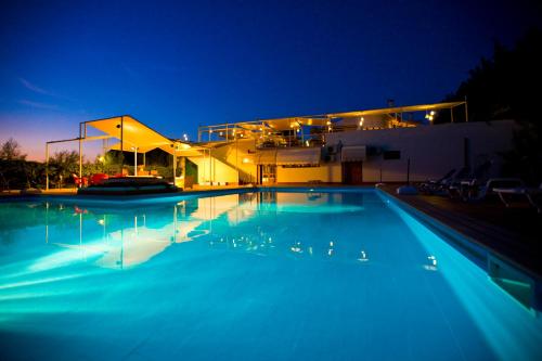 a large swimming pool in front of a building at night at Hotel Pocho in San Vito lo Capo