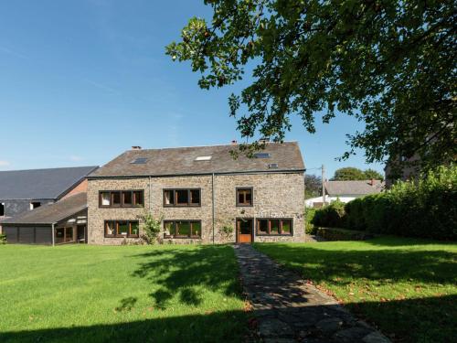 une grande maison en pierre avec une cour verdoyante dans l'établissement Cosy holiday house near La Roche, à Rendeux