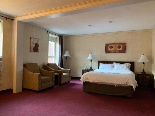 Habitación de hotel con cama y silla en Royal Inn and Suites at Guelph en Guelph