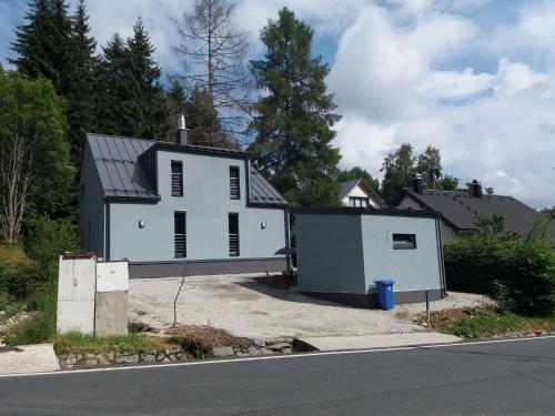 a white house with a garage next to a street at Quaint Holiday Home in elezn Ruda near Ski Area in Železná Ruda
