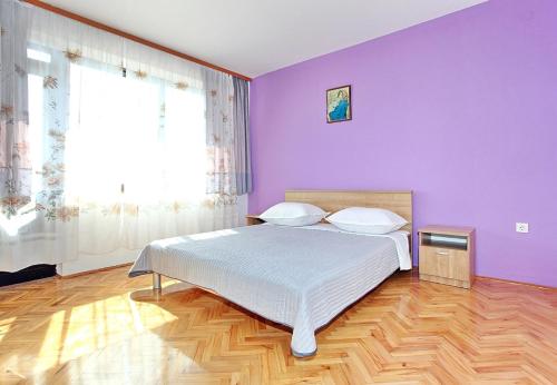 a purple bedroom with a bed and a window at Apartments Sorić in Bibinje