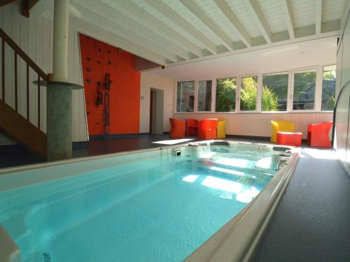 una gran piscina en una habitación con sillas naranjas en Holiday home close to the Robertville lake en Waimes