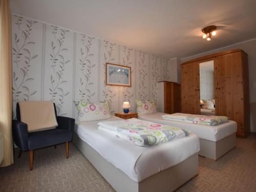 een hotelkamer met 2 bedden en een stoel bij Wonderful Apartment in Elpe with Garden in Kröpelin