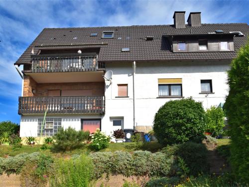 a large white house with a balcony at Quaint Apartment in Gro almerode near the Forest in Großalmerode