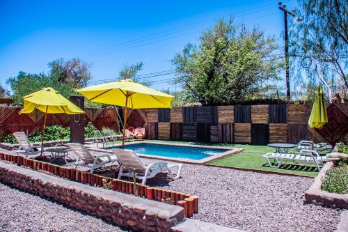 a backyard with a pool with chairs and umbrellas at San Pedro Domos in San Pedro de Atacama