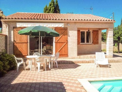 a patio with a table and chairs and an umbrella at Beautiful holiday home in Argeliers with pool in Argeliers