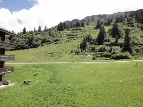 a grassy field with a winding road on a mountain at South facing flat with balcony in Méribel