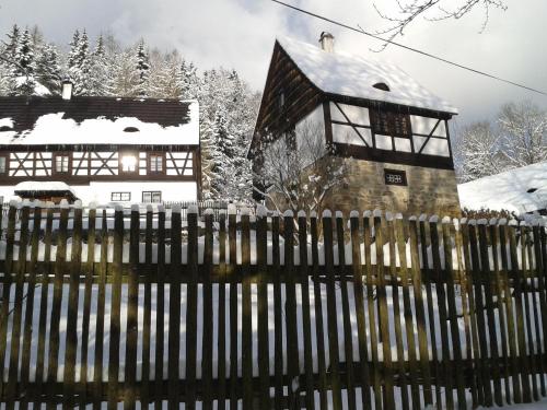 ein Haus hinter einem Zaun mit schneebedeckten Bäumen in der Unterkunft Holiday Home in Nejdek in West Bohemia with garden in Nejdek