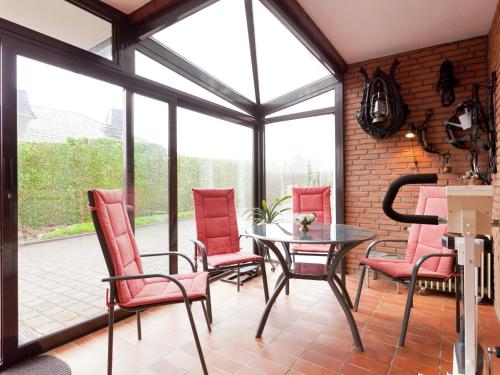 un salón acristalado con sillas rojas y mesa de cristal en Apartment in Eifel with children s playground en Lirstal