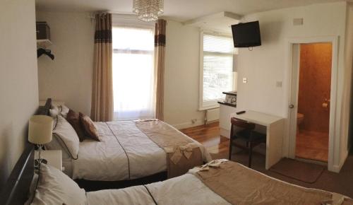 1 dormitorio con 2 camas, escritorio y TV en Admiral Hotel, en Scarborough