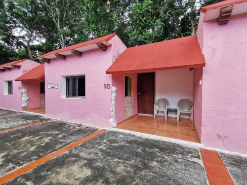 a row of pink houses with chairs in a parking lot at Hotel Doralba Inn Chichen in Chichén-Itzá
