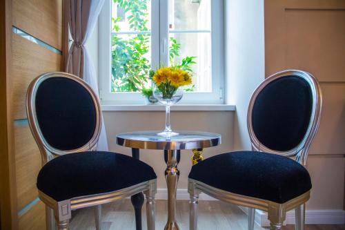 two chairs and a table with a vase of flowers at Peninsula Luxury Rooms in Zadar