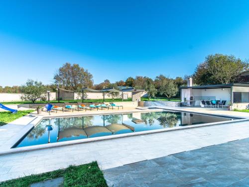 Beautiful Villa in Vrsar with Swimming Pool في فيرسار: مسبح مع كراسي وطاولات في ساحة