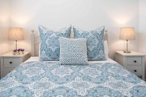 a bed with blue and white pillows and two lamps at Beach Folly - Whitianga in Whitianga