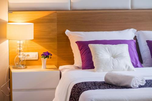 a bedroom with a bed with purple and white pillows at Peninsula Luxury Rooms in Zadar