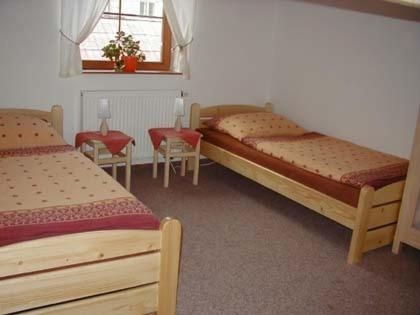 ヴルフラビーにあるApartmány Vrchlabíのベッドルーム1室(ベッド2台、テーブル2台、椅子付)