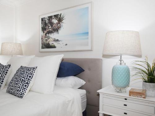 a bedroom with a bed with pillows and a table with two lamps at Windmill 4 Two Bedroom Beachside Apartment on Parkyn Parade in Mooloolaba