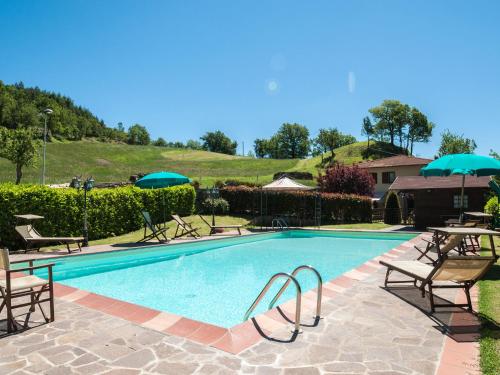 uma piscina com cadeiras e guarda-sóis num resort em Belvilla by OYO Villa Lonanno em Pratovecchio