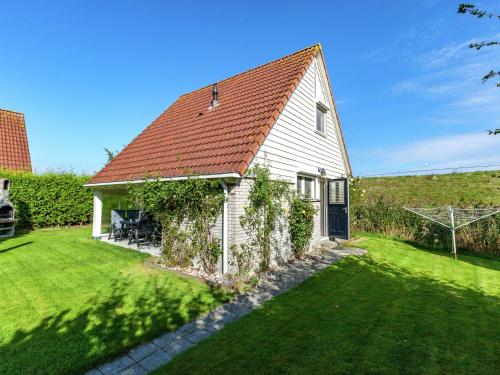 ein weißes Haus mit einem roten Dach und einem Hof in der Unterkunft Superb holiday home near the Lauwersmeer in Oostmahorn