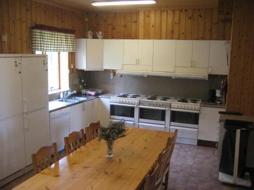 a kitchen with a wooden table and white appliances at Farmhouse with facilities in the middle of nature in Sysslebäck