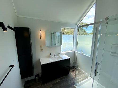 a bathroom with a sink and a glass shower at Chamberlain House - 3 bedroom house by Manly beach in Auckland