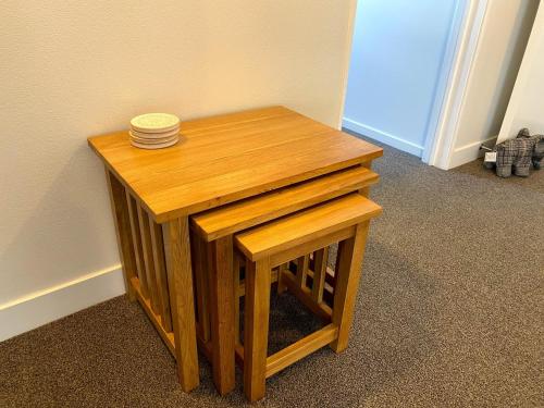 a small wooden table with a stack of plates on it at Chamberlain House - 3 bedroom house by Manly beach in Auckland