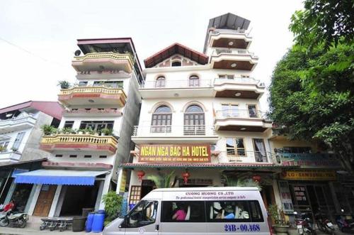 a van parked in front of a tall building at Ngan Nga Bac Ha Hotel in Bắc Hà