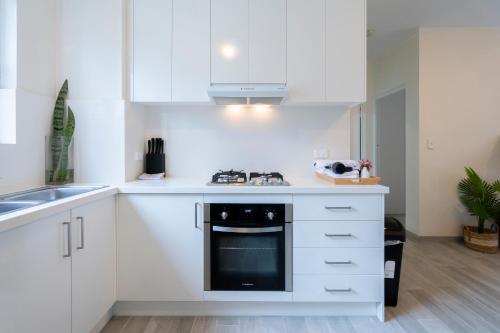 a kitchen with white cabinets and a stove top oven at Lotus Stay Manly - Apartment 29B in Sydney