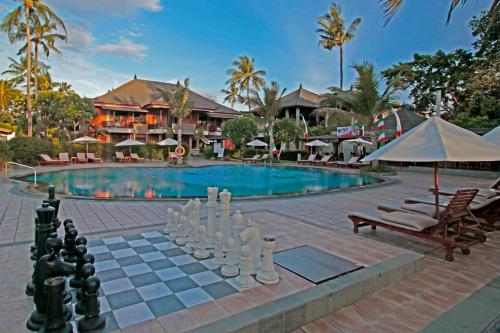 a patio with a pool, chairs, and a pool table at The Jayakarta Bali Beach Resort in Legian