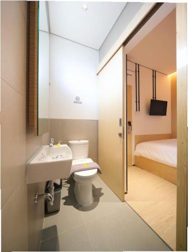 a bathroom with a sink and a toilet and a bed at Cool Living in Jakarta