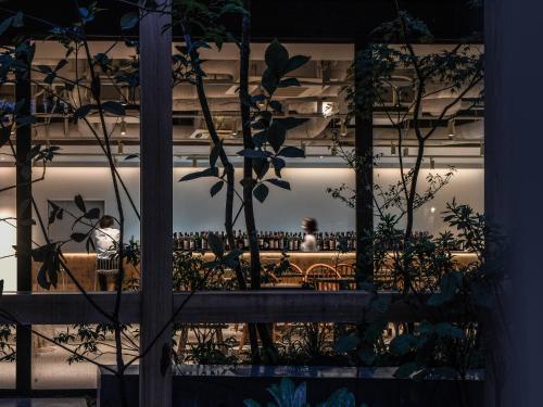 a window of a building with people sitting on a bench at REF Kyoto Hachijoguchi by VESSEL HOTELS in Kyoto