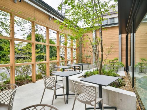 a patio with tables and chairs and windows at REF Kyoto Hachijoguchi by VESSEL HOTELS in Kyoto