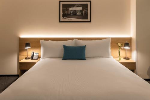 a bedroom with a large white bed with a blue pillow at Hotel Room @ 89 Courtenay Place in Wellington