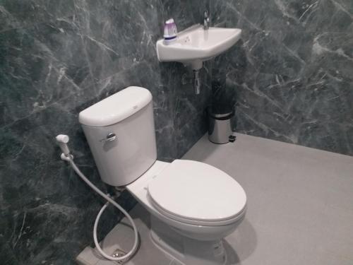 a bathroom with a white toilet and a sink at Saney Apartment in Ban Nong Ka Cha
