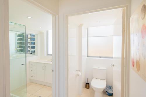 a bathroom with a toilet and a glass shower at Berkeley on the Beach in Gold Coast