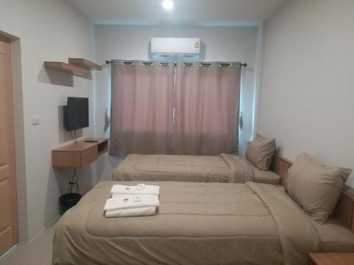 a bedroom with two beds with towels on them at Saney Apartment in Ban Nong Ka Cha