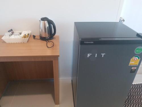 a small refrigerator sitting next to a wooden desk at Saney Apartment in Ban Nong Ka Cha