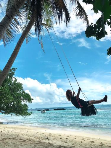 a woman swinging on a swing on a beach at Samura Maldives Guest House Thulusdhoo in Thulusdhoo