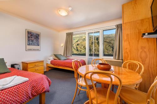 a room with a table and chairs and a bed and a window at Kasees Apartments & Mountain Lodge in Thredbo