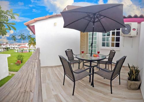 une terrasse avec une table, des chaises et un parasol dans l'établissement HominngBird Acapulco, à Acapulco