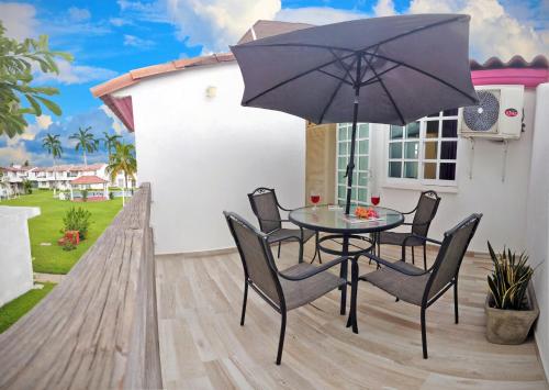 a patio with a table and chairs and an umbrella at HominngBird Acapulco in Acapulco