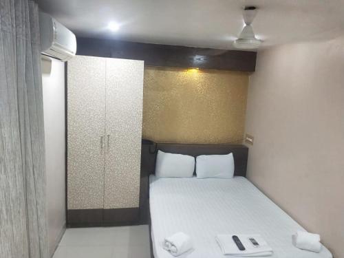 a small bedroom with a bed with white sheets at Hotel Eastern Plaza in Kolkata