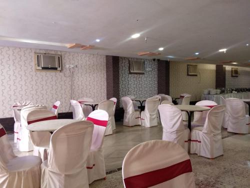 a room filled with tables and white chairs at Hotel Eastern Plaza in Kolkata