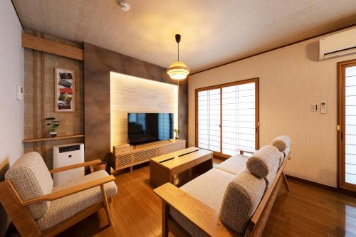 sala de estar con mesa, sillas y TV en Shirakabanoyado - Ryogetsu, en Osaka