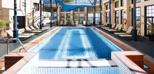 a swimming pool with lounge chairs in a building at Stamford Grand Adelaide in Adelaide