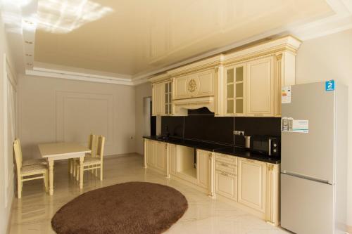 kuchnia z białymi szafkami, stołem i lodówką w obiekcie Residential Complex Central 261 w mieście Ałma-Ata