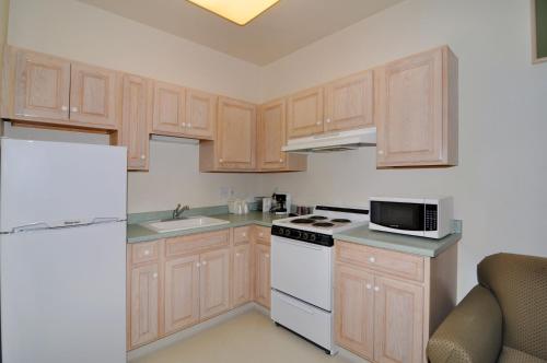 a kitchen with wooden cabinets and a white appliance at Marinwood Inn & Suites in Novato