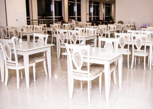a white dining room with white tables and chairs at Liberty Fly Hotel in Adler